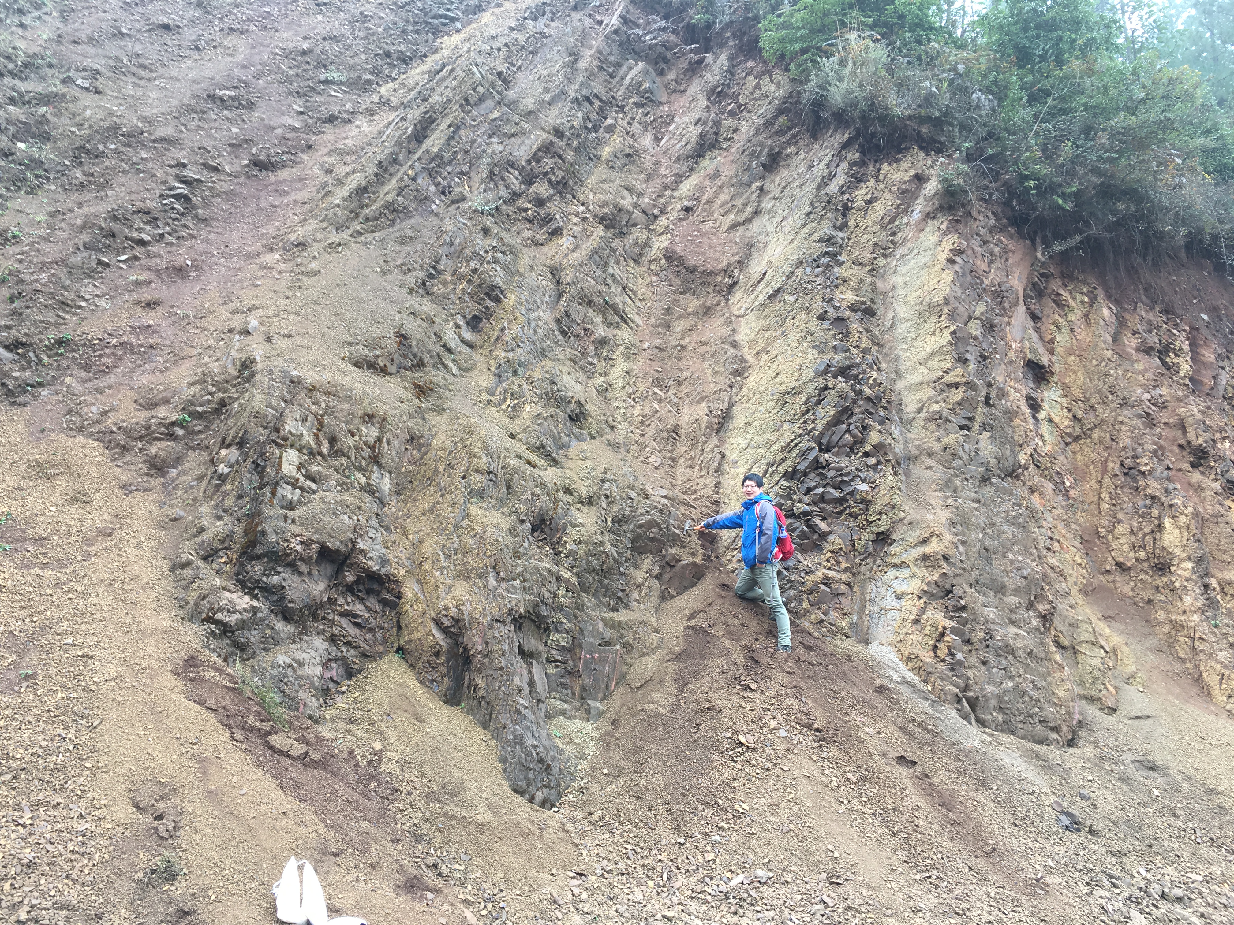Dr. Yadong Sun pointing to the terrestrial Permo-Triassic boundary at Chahe
